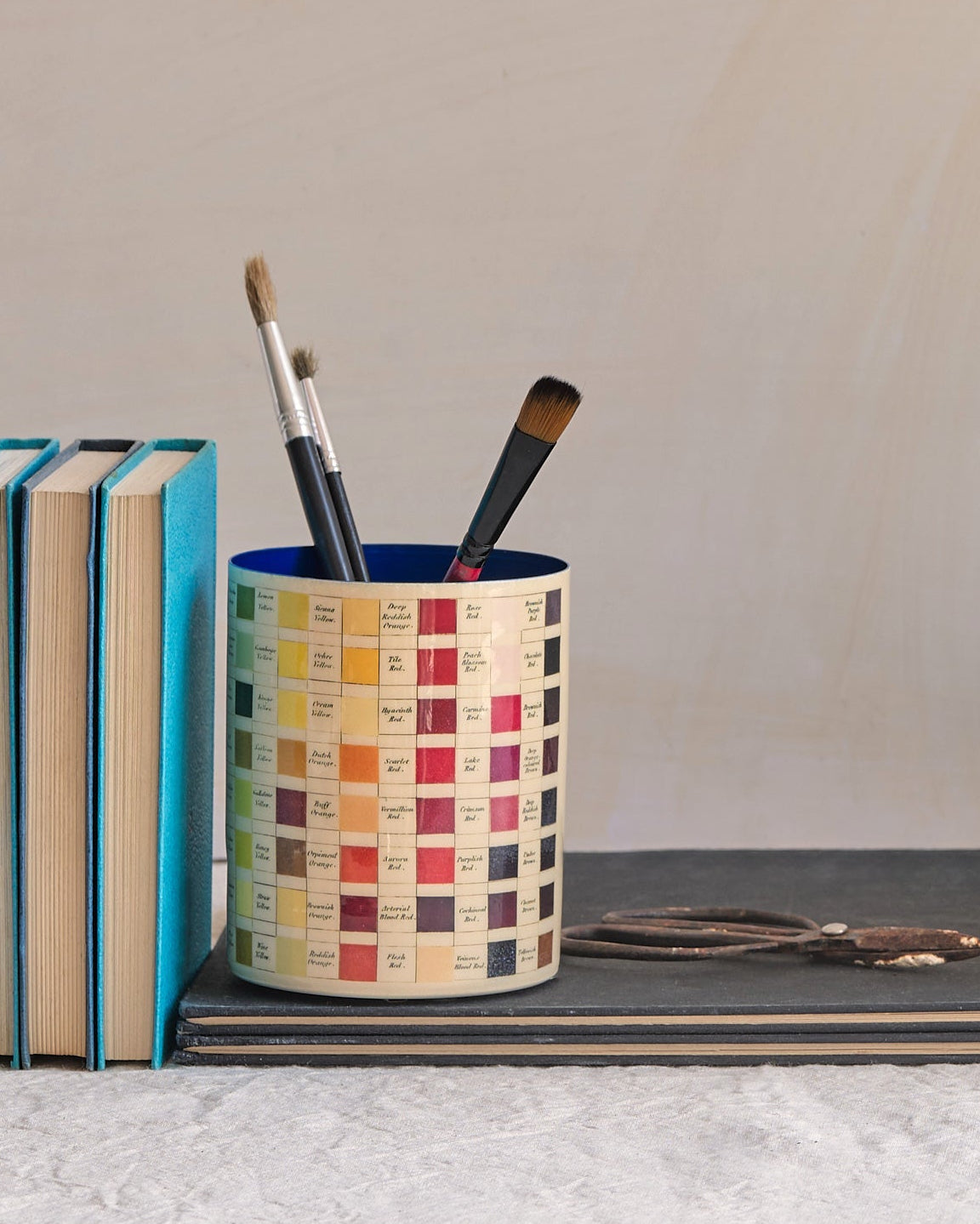 Desk setup with stationery items including books, cups, and a vase.