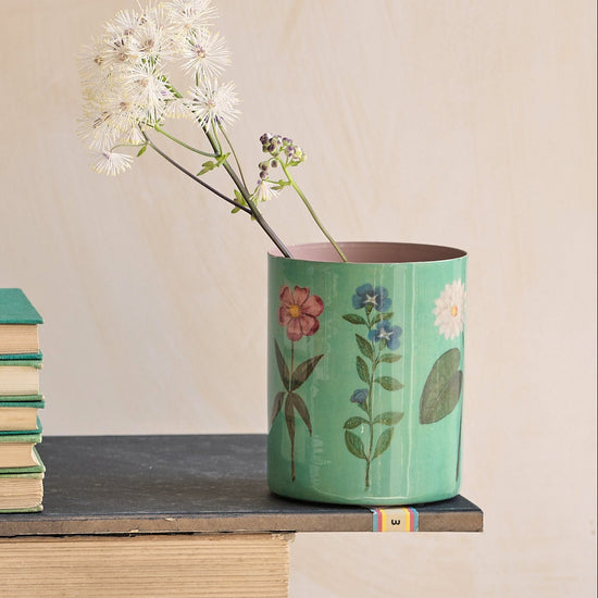 Desk setup with stationery items including books, cups, and a vase.