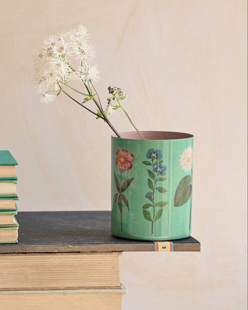 Desk setup with stationery items including books, cups, and a vase.