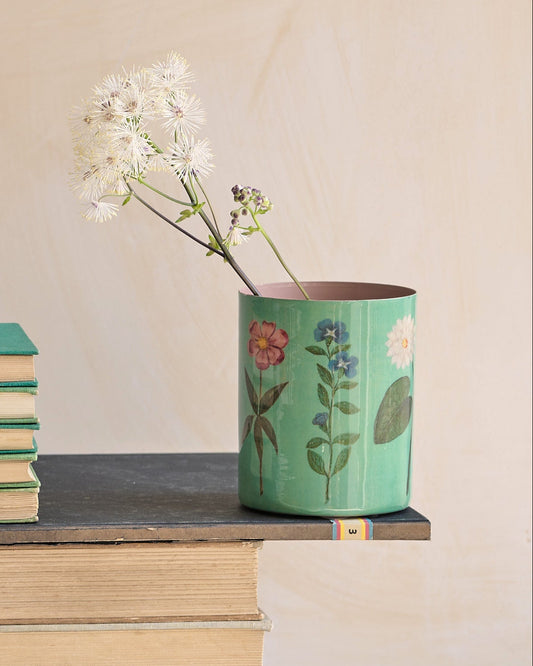 Desk setup with stationery items including books, cups, and a vase.