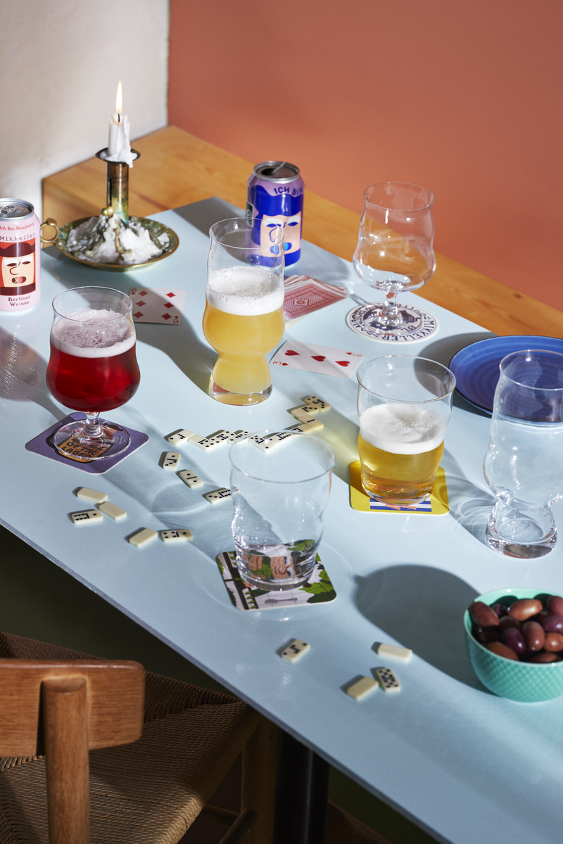 Table with various drinks, snacks, and playing cards in a casual setting.