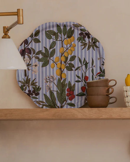 Kitchen shelves with decorative plates, cups, and utensils against a neutral wall.
