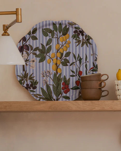 Kitchen shelves with decorative plates, cups, and utensils against a neutral wall.