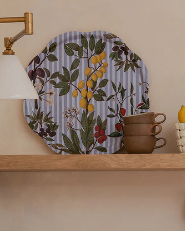 Kitchen shelves with decorative plates, cups, and utensils against a neutral wall.