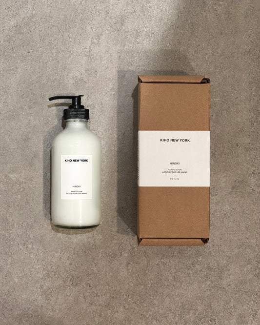 White bottle with black pump and brown cardboard box on a gray concrete surface, featuring 'Kiho New York' branding.