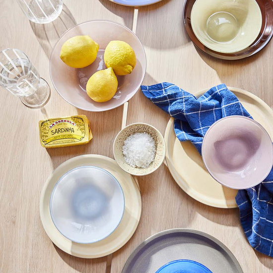 Table setting with various bowls, lemons, and a salt container on a wooden surface.