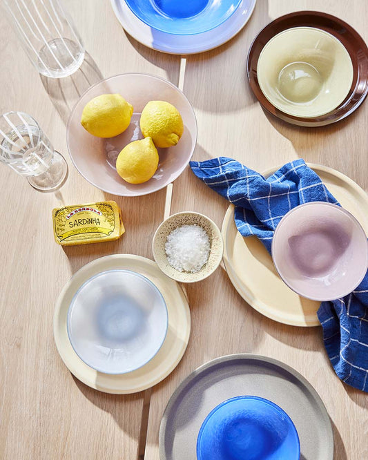 Table setting with various bowls, lemons, and a salt container on a wooden surface.