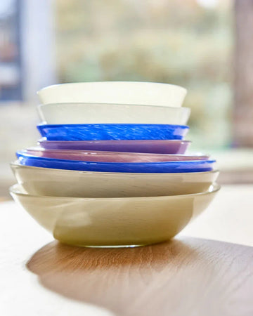 Stack of colorful ceramic bowls on a wooden surface with a blurred background