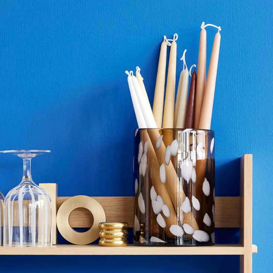 Decorative items including candles and a vase on a shelf against a blue wall