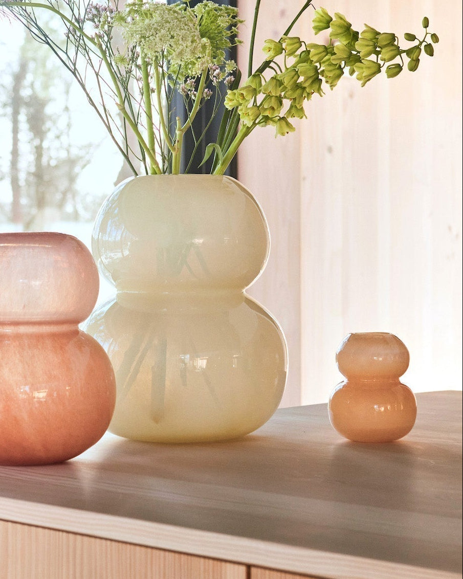 Three glass vases on a wooden cabinet with a window in the background