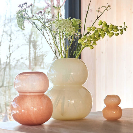 Three glass vases on a wooden cabinet with a window in the background