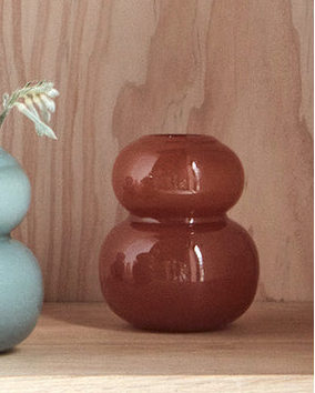 Red ceramic vase on a wooden surface with a light wood background