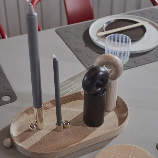 Wooden tray with various items including a candle holder and small containers on a table.