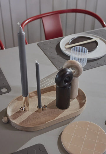 Wooden tray with various items including a candle holder and small containers on a table.