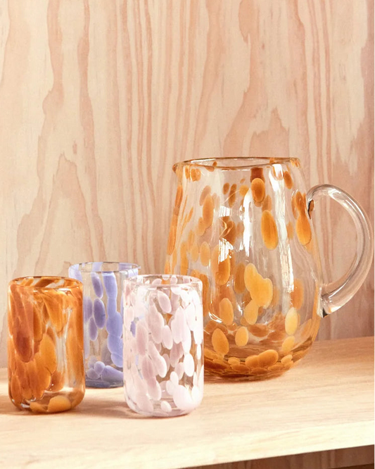 Set of glass mugs with abstract designs on a wooden surface