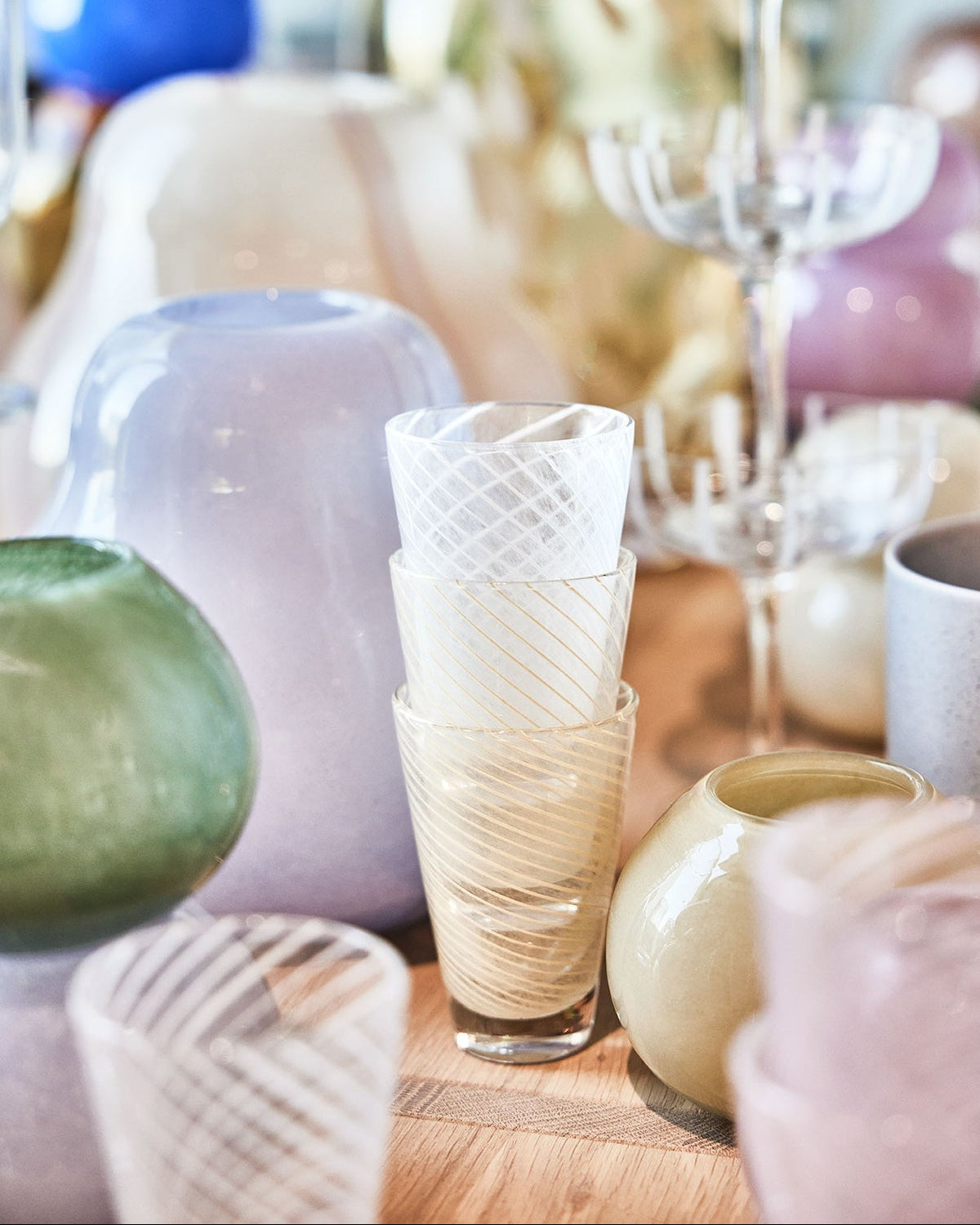 Decorative glassware and ceramic items on a wooden surface with a blurred background