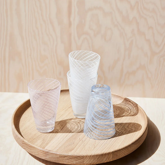 Three glass tumblers on a wooden tray against a light wood panel background