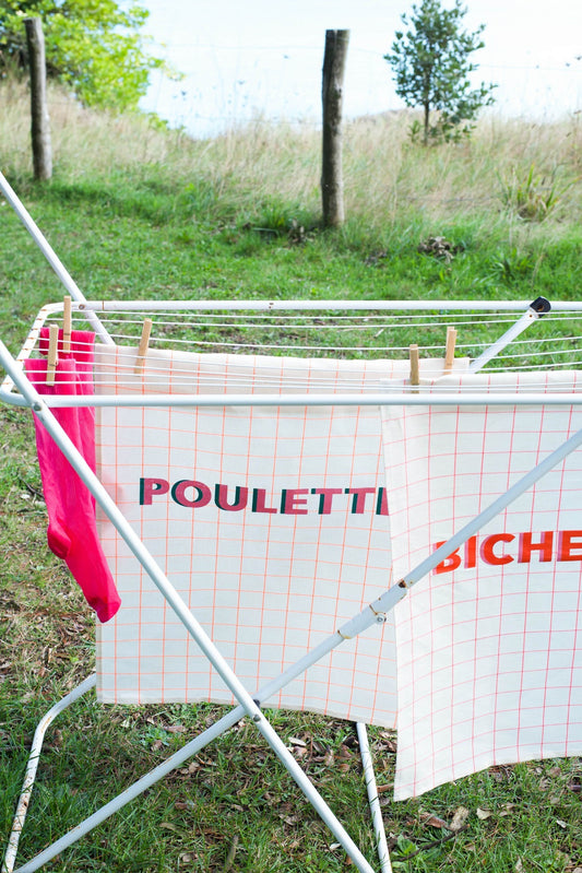 Outdoor drying rack with clothes and 'POULETTI' sign in a grassy area
