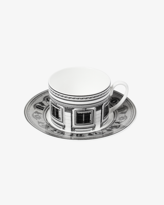 White teacup and saucer with decorative black patterns on a white background