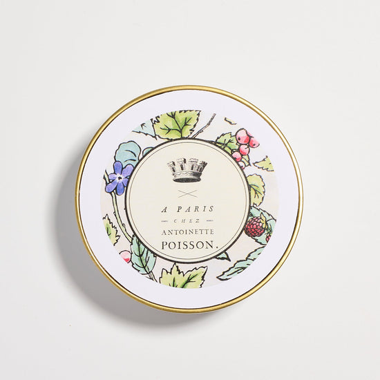Top view of a jar lid with a gold rim and a floral design surrounding the text “A Paris Chez Antoinette Poisson”