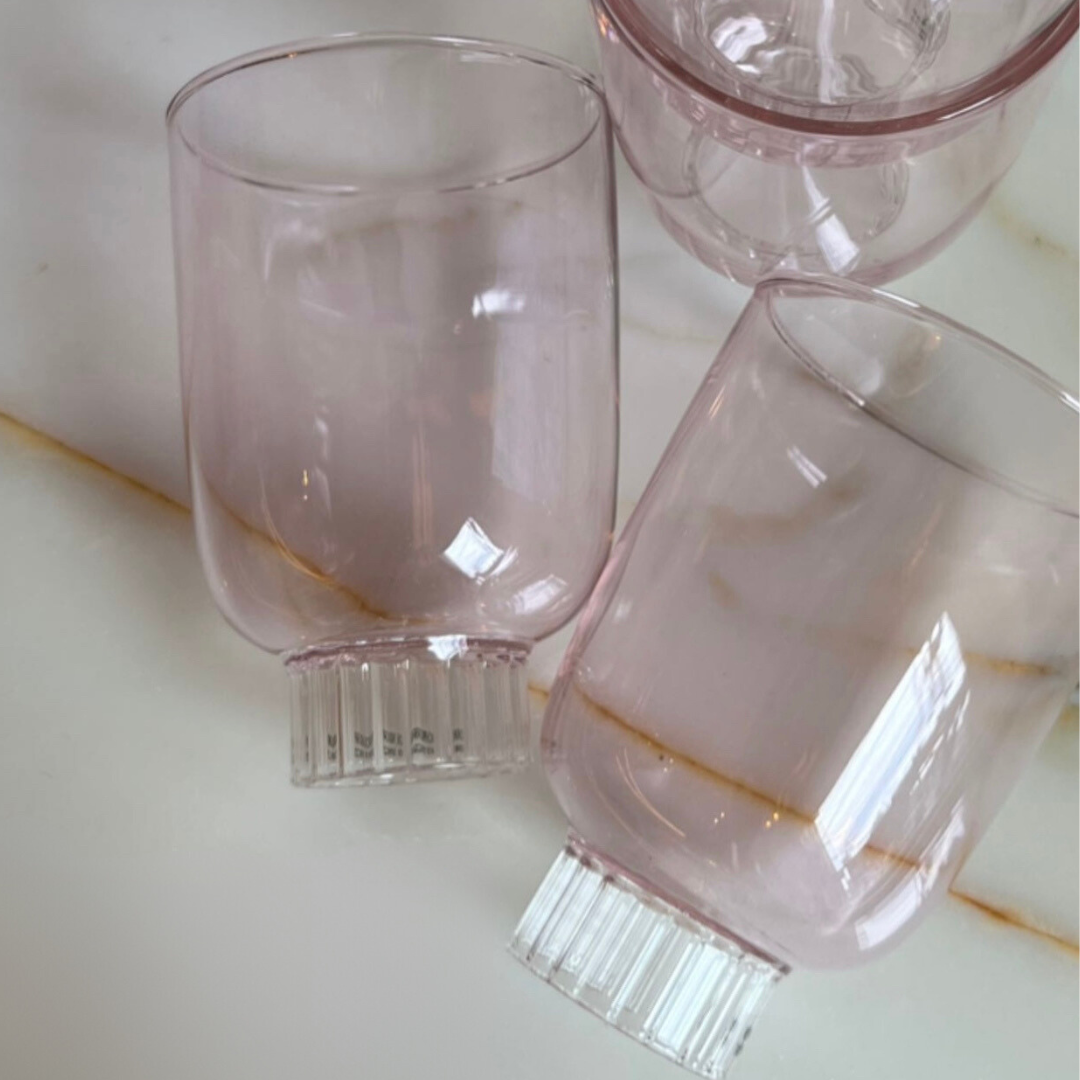 Three pink glasses on a light-colored surface