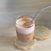 Glass of layered coffee drink with a straw on a textured surface