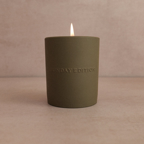 Green candle with 'Sunday Edition' branding on a beige background