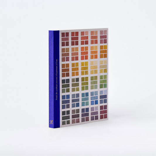 A color reference book with a deep blue spine and a front cover displaying a grid of color swatches in many hues, photographed on a clean white background.