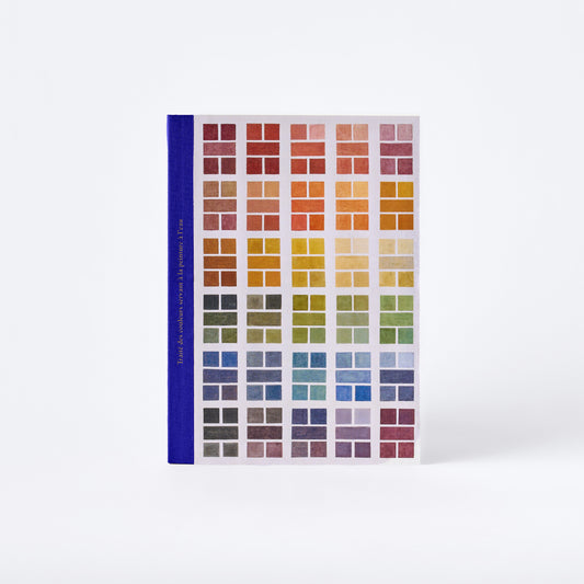 A vertical color chart book with a blue spine and a grid of many small color swatches, photographed upright on a clean white background.