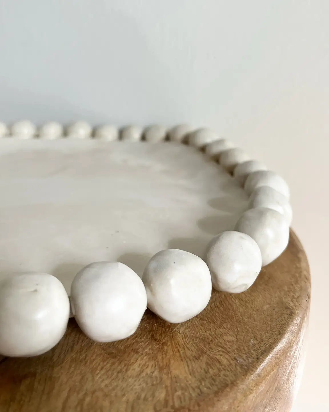 White beaded bracelet on a wooden surface with a light gray background