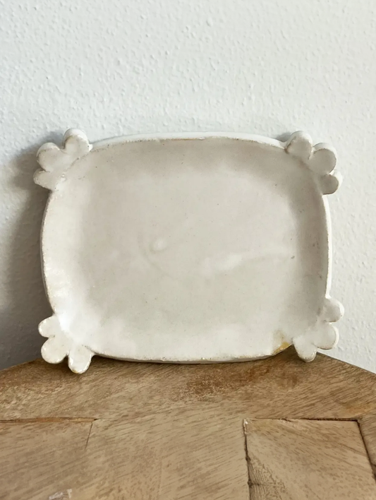 Rectangular ceramic plate with decorative feet on a wooden surface