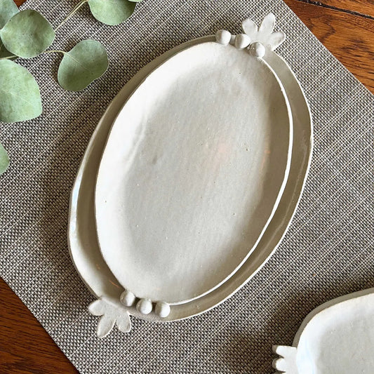 White ceramic platter with floral design on a textured placemat