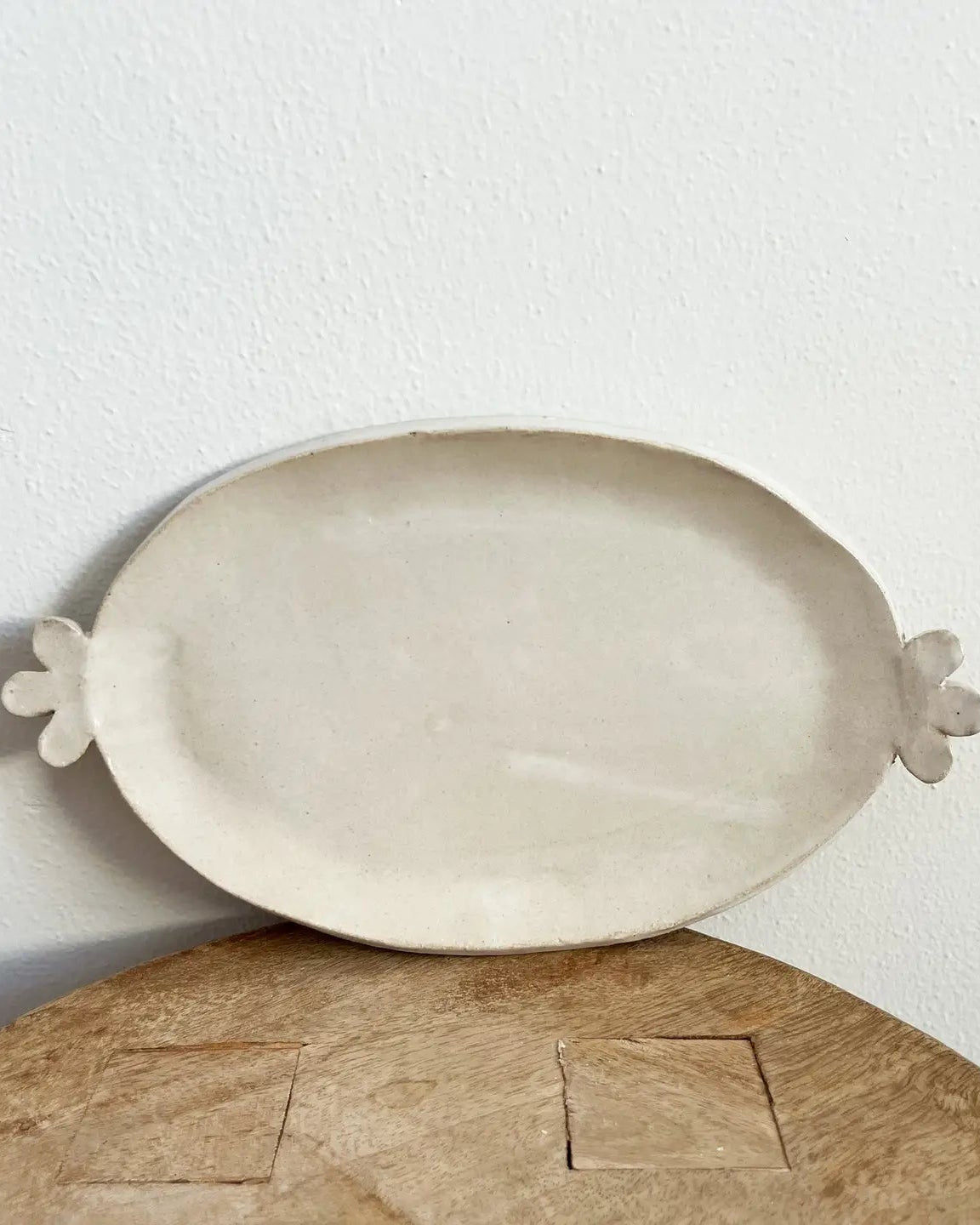 White ceramic platter with floral handles on a wooden surface
