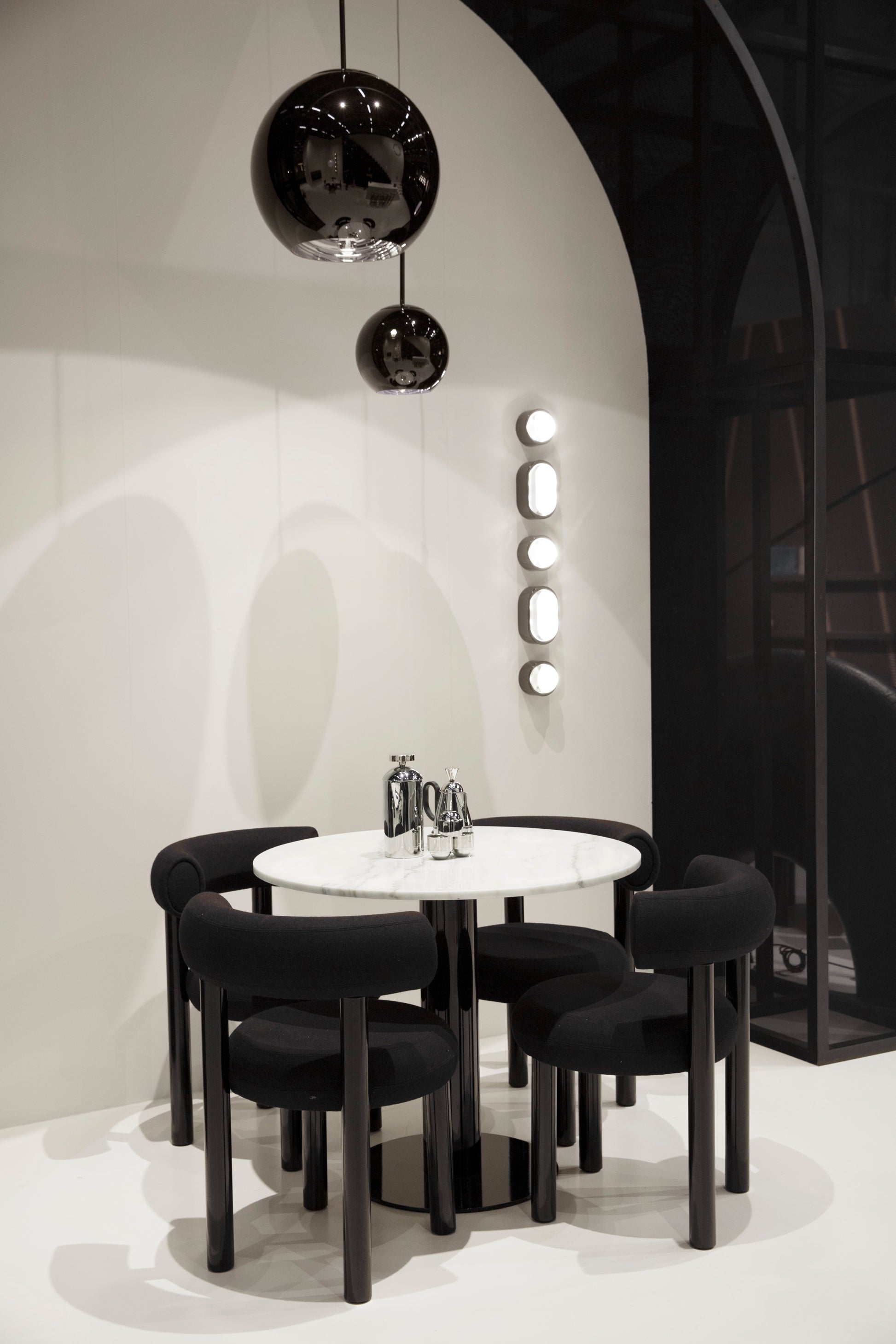 Modern black and white dining area with round table with brew cafetiere and chairs.