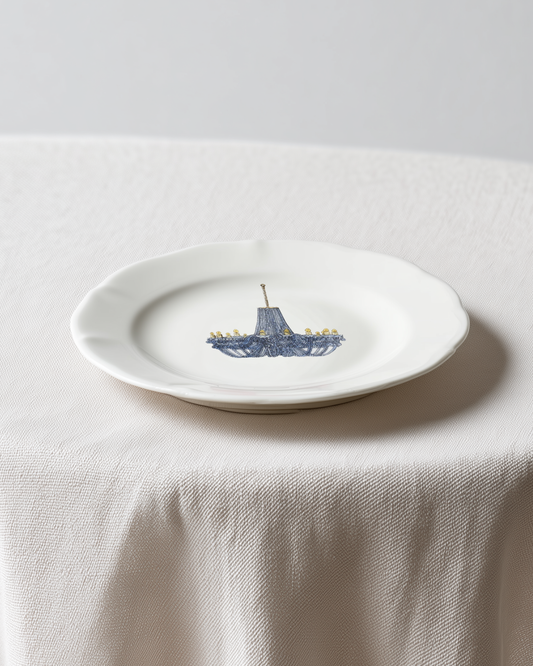 White plate with a blue ship design on a white tablecloth