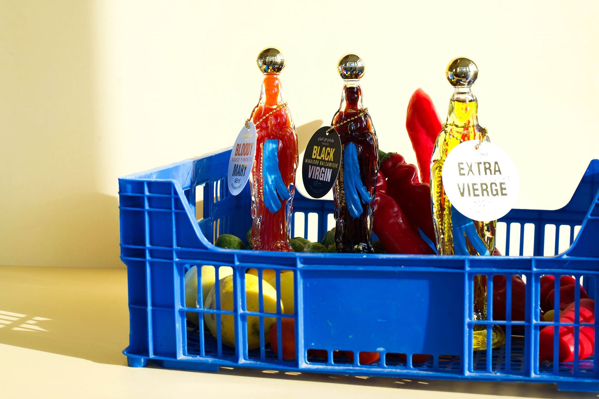 Blue crate with bottles of olive oil and vegetables on a light background