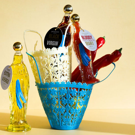Blue decorative basket with hot dogs, buns, and a bottle of hot sauce on a yellow background