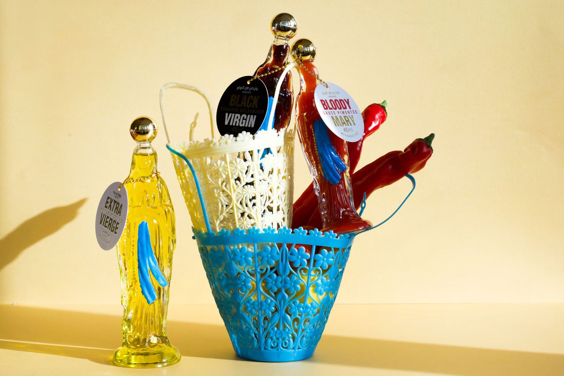 Blue decorative basket with hot dogs, buns, and a bottle of hot sauce on a yellow background