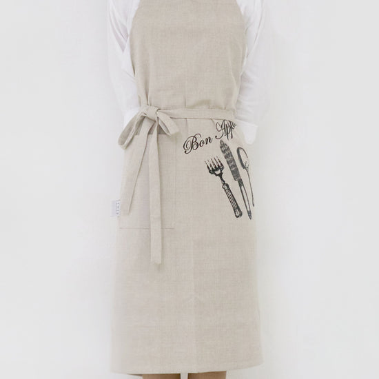 Person wearing a beige apron with graphic designs on a white background