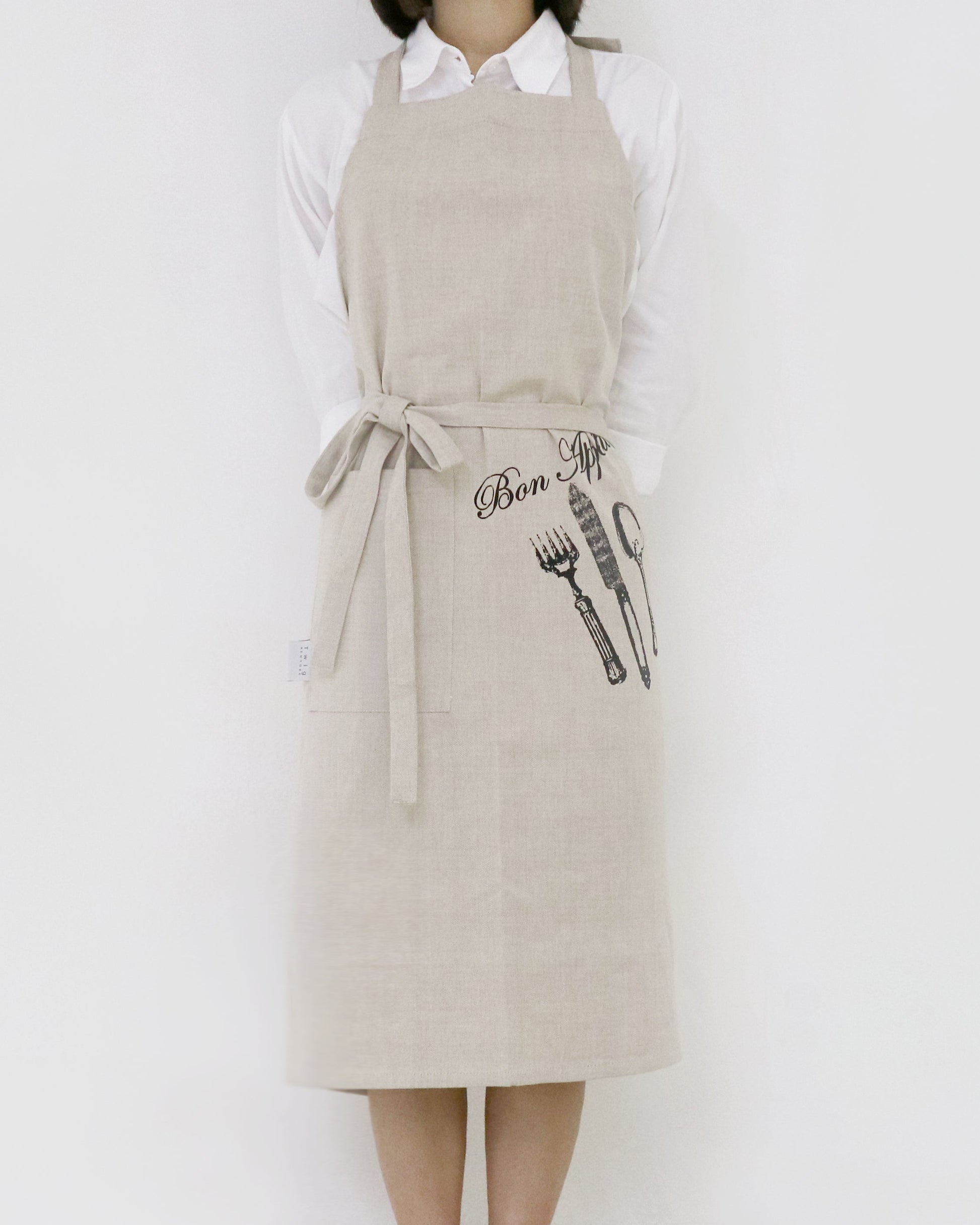 Person wearing a beige apron with graphic designs on a white background
