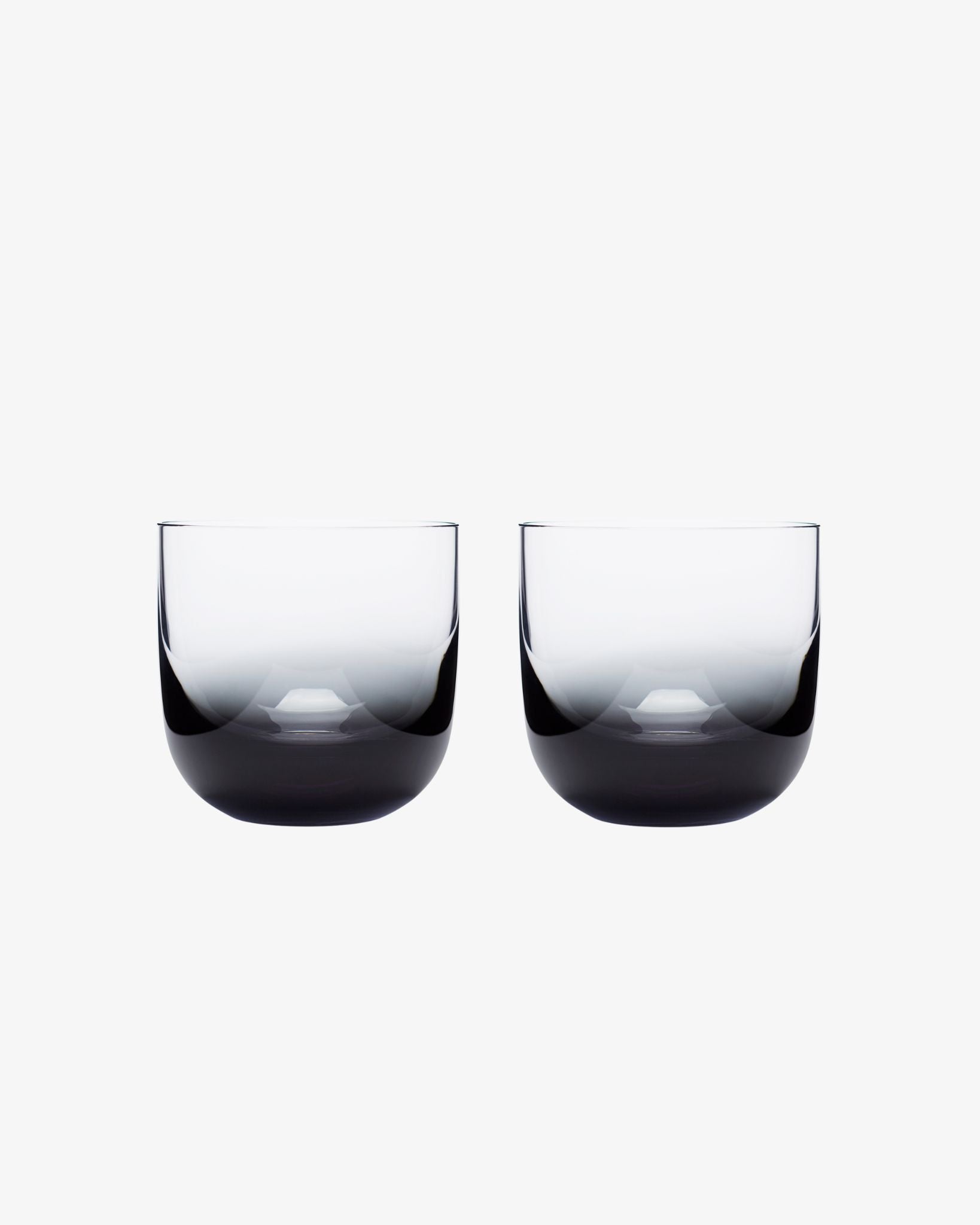 Two black whiskey glasses on a white background