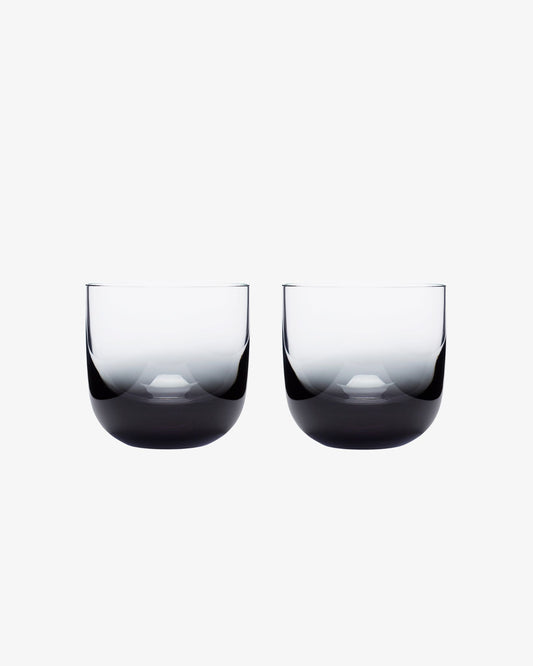 Two black whiskey glasses on a white background