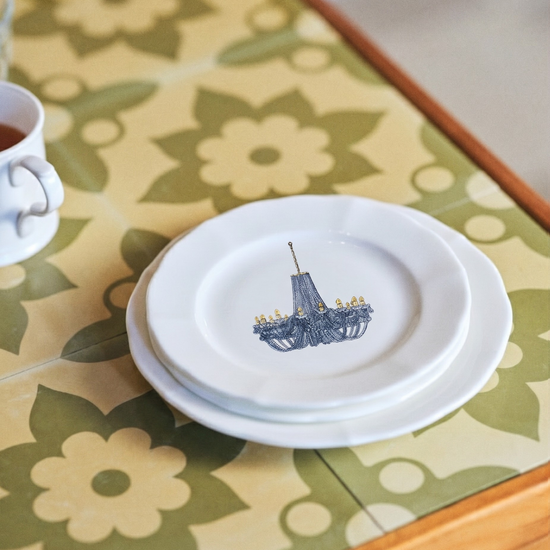 White plate with a blue design on a floral tablecloth