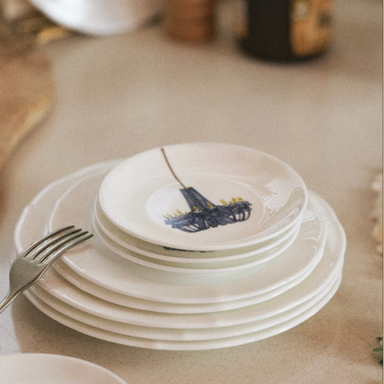 Stack of white ceramic plates with colorful designs on a kitchen counter.