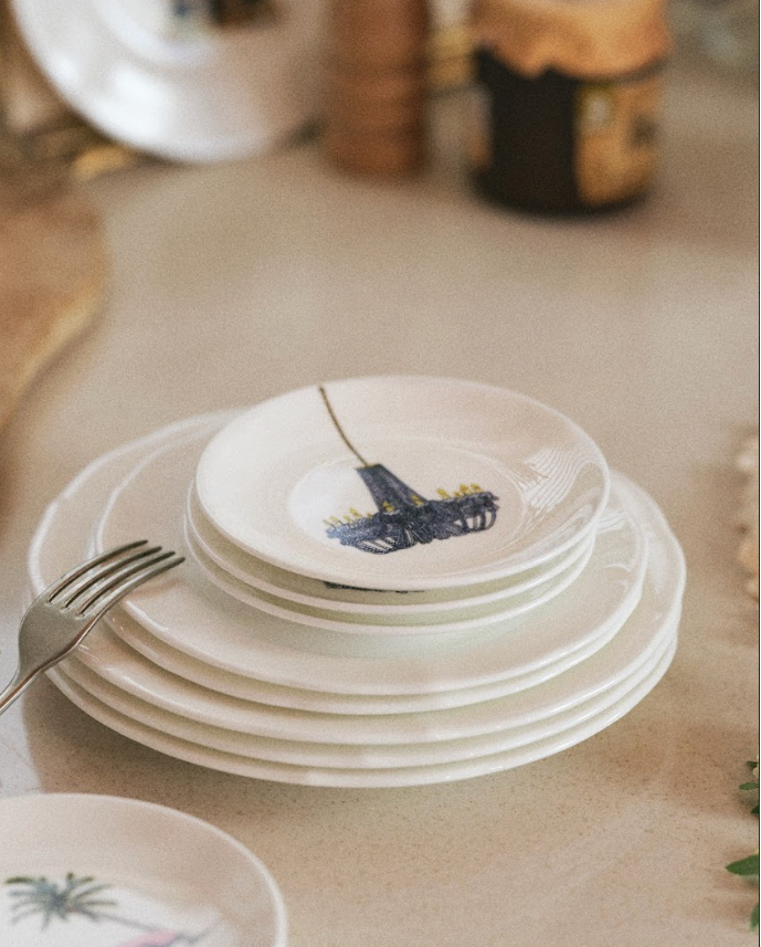 Stack of white ceramic plates with colorful designs on a kitchen counter.