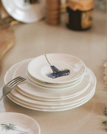 Stack of white ceramic plates with colorful designs on a kitchen counter.
