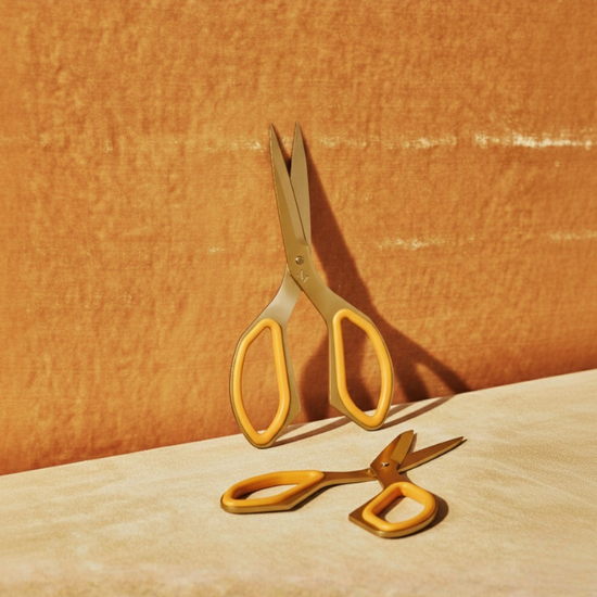 Gold scissors on a textured orange surface