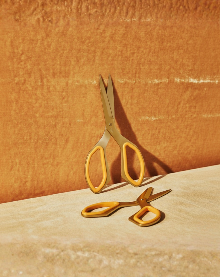 Gold scissors on a textured orange surface