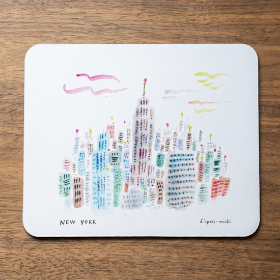 Colorful illustration of New York cityscape on a white mouse pad, placed on a wooden surface.