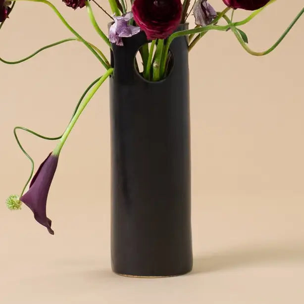 Black vase with flowers on a beige background